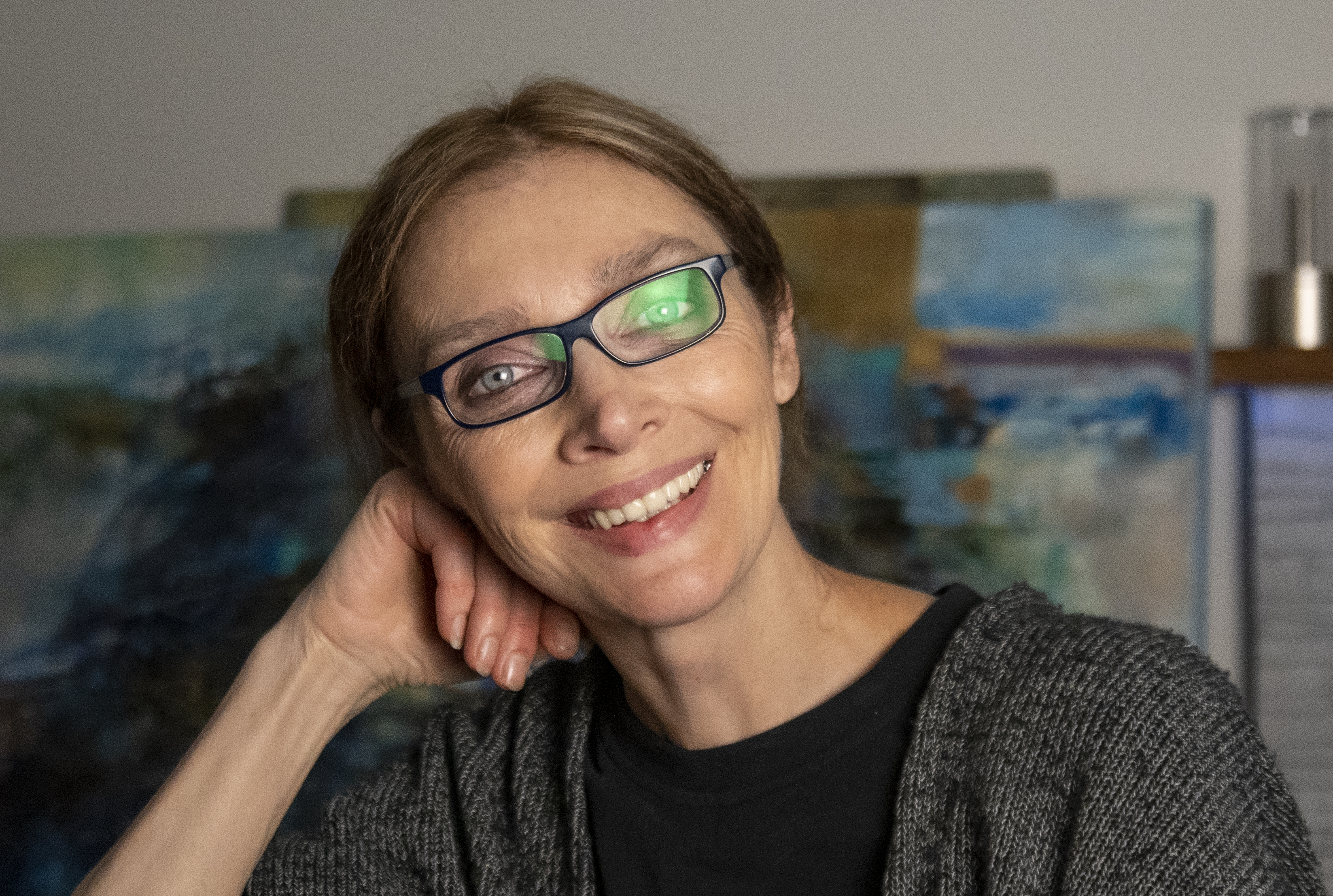 Inna Orlik in her studio, her paintings visible behind her.